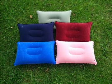 Five inflatable travel pillows in different colors on grass