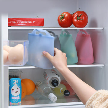 Person reaching into a refrigerator with colorful silicone bags; Square-shaped 1000ml silicone food storage bag in semi-transparent white