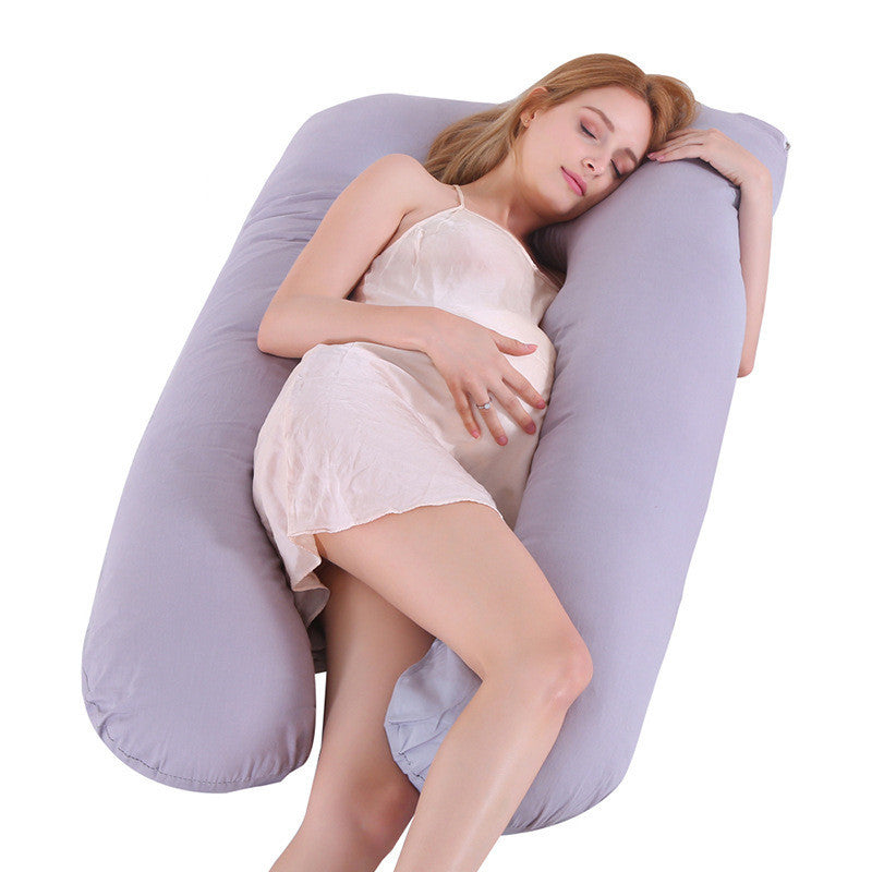 Woman lying on a large U-shaped pillow against a white background