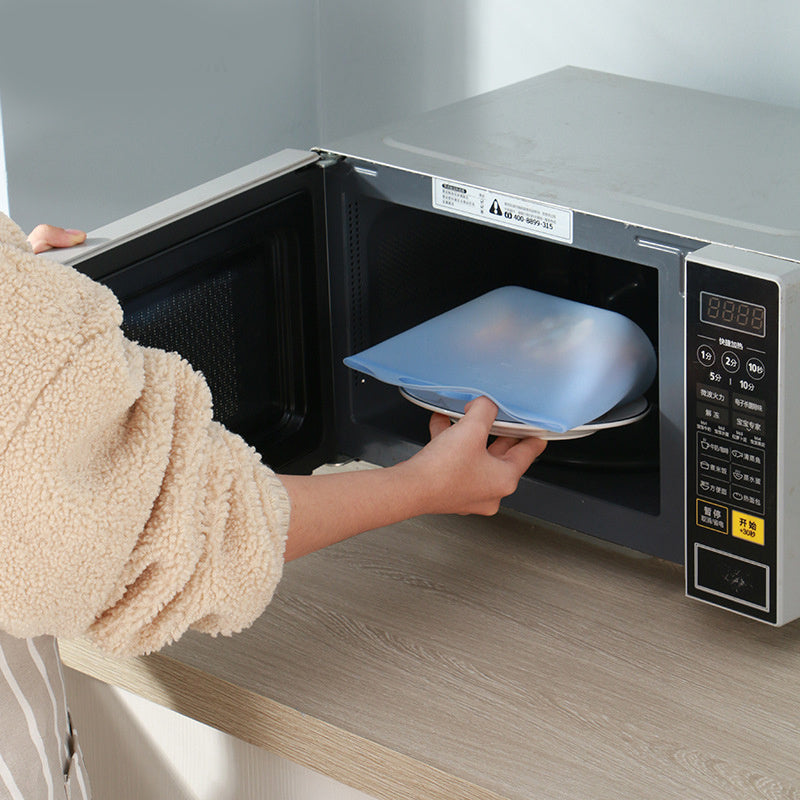 Person reaching into a refrigerator with colorful silicone bags; Square-shaped 1000ml silicone food storage bag in semi-transparent white