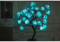 Decorative LED lamp shaped like a tree with blue glowing flowers on a dark background.