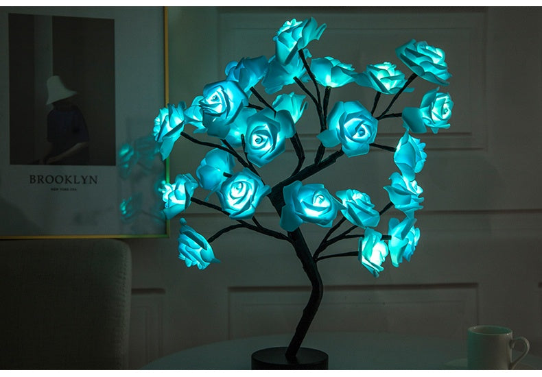 Decorative LED lamp shaped like a tree with blue glowing flowers on a dark background.