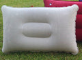 White inflatable pillow on grass with a red object in the background