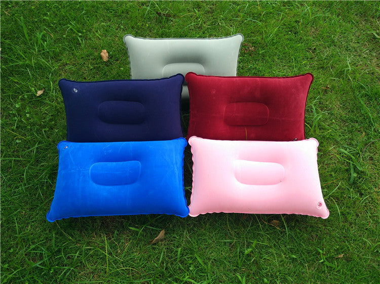 Five inflatable travel pillows in different colors on grass