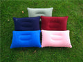 Five inflatable travel pillows in different colors on grass