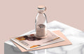 Portable rechargeable USB blender with a metallic cap on a magazine with a pink background