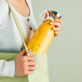 Person holding a yellow Portable rechargeable USB blender labeled 'Fresh Juice' against a light green background
