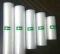Five rolls of clear plastic sheeting with green directional arrows on a dark background