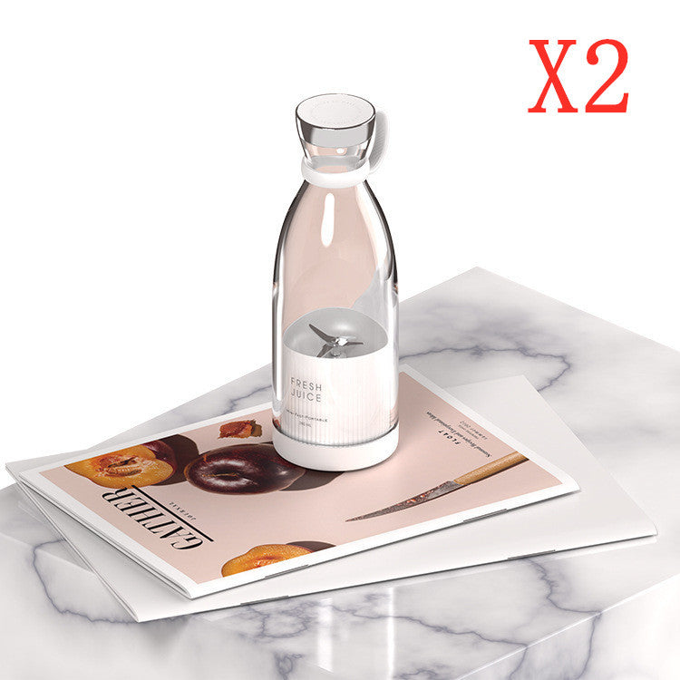 Clear Portable rechargeable USB blender with a label on a magazine on a marble surface, with 'X2' in red text above.