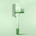 Green pet grooming brush on a light green background