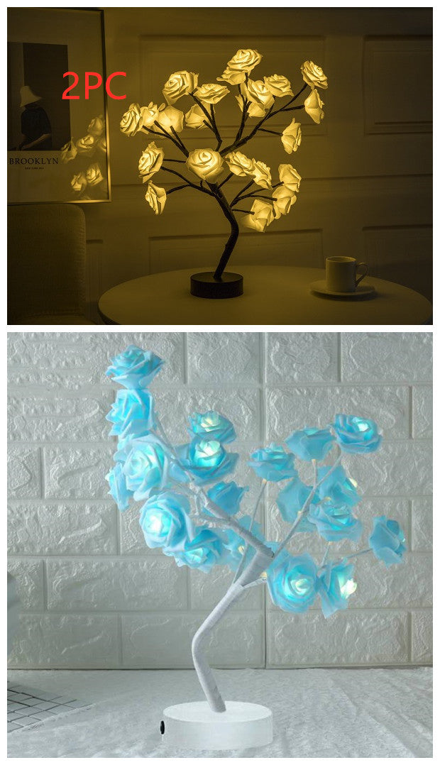 Two LED rose tree lights, one yellow and one blue, on a table with a white brick wall background
