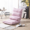 Pink floor pillow on a wooden floor with a table and books in the background