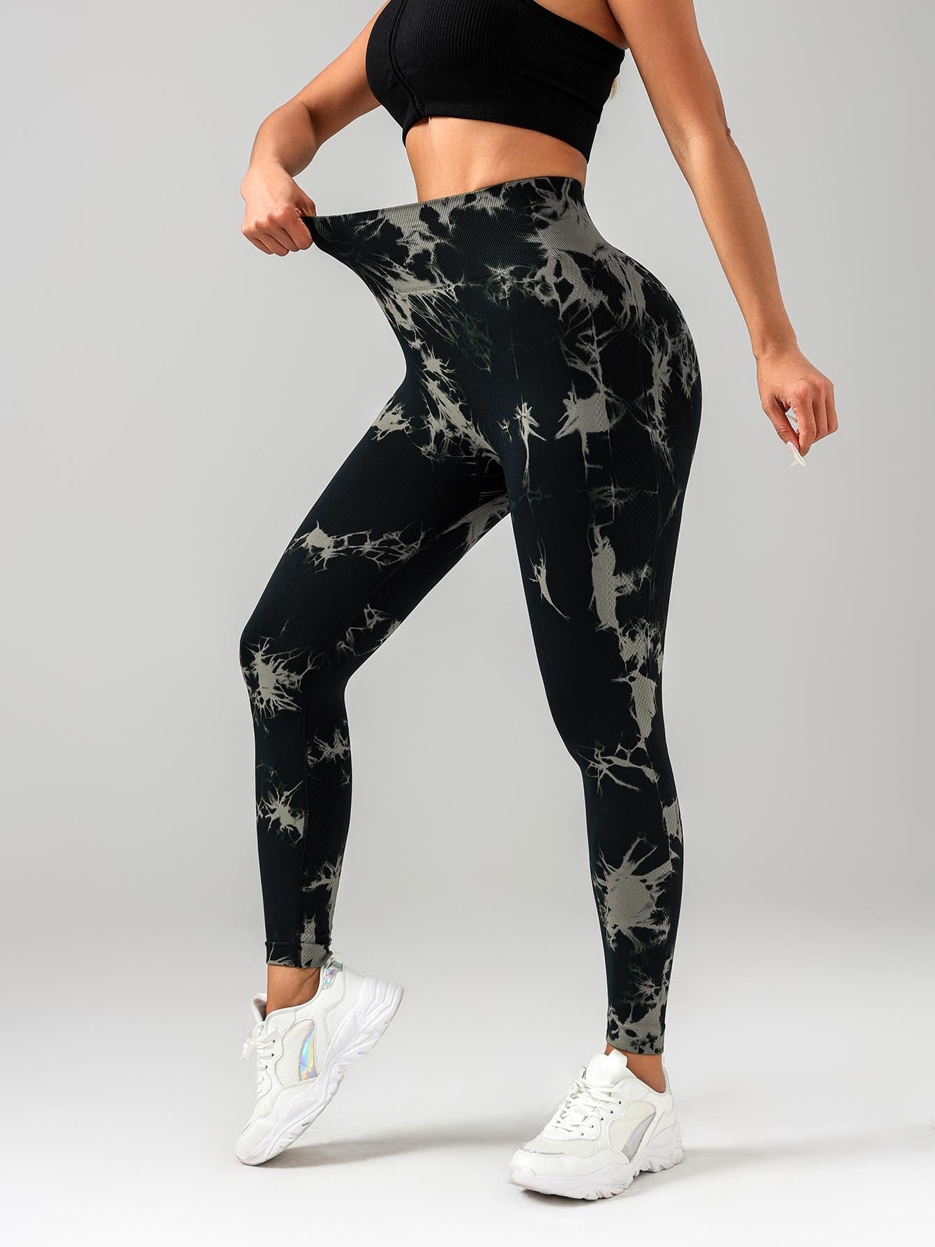 Person wearing black tie-dye leggings and a black top on a gray background