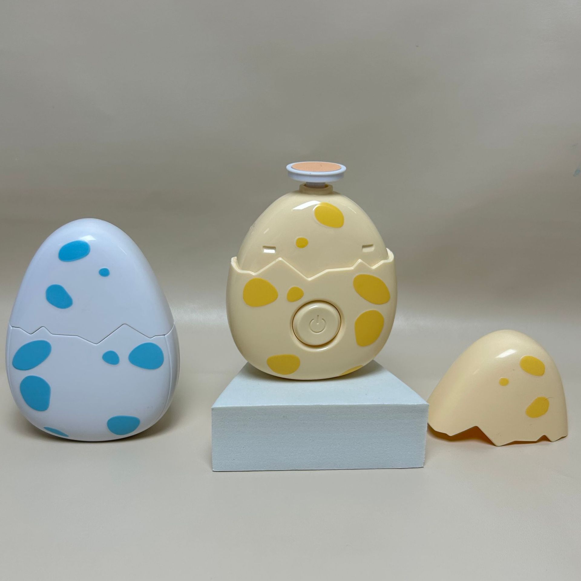 Three eggs type Children electric nail grinder with soft grinding head for safe baby nail trimming with polka dot patterns on a neutral background