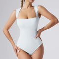 Woman wearing a light blue swimsuit against a gray background