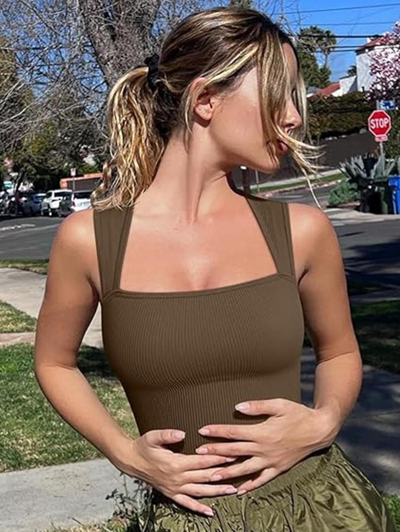 Woman wearing a brown workout romper jumpsuit and green skirt standing on a street