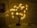 Decorative LED rose lamp shaped like a tree with illuminated rose flowers on a table.