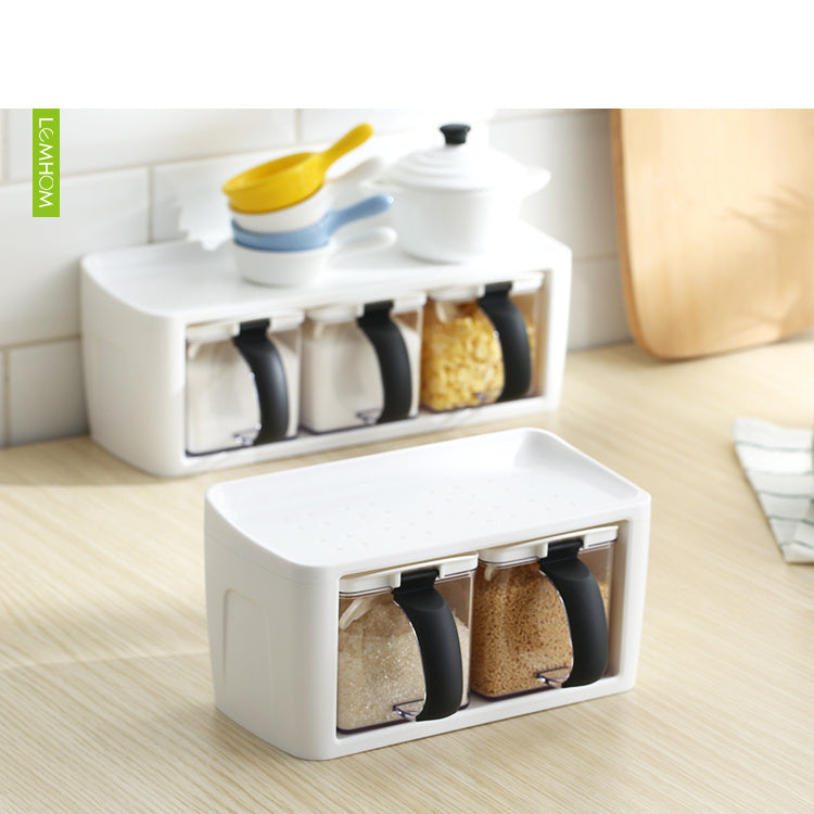 White kitchen storage box with black handles containing various grains on a wooden surface