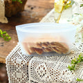 Clear silicone food storage bag with crackers on a lace tablecloth; Reusable silicone fridge bag for fruits and vegetables