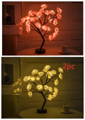 Decorative LED tree lights in pink and white on a table with a cup.