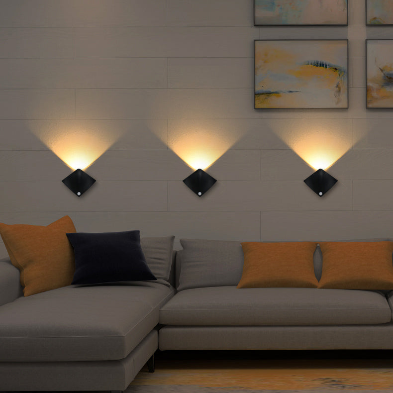Modern living room with a gray sectional sofa, orange and black cushions, and wall-mounted lights