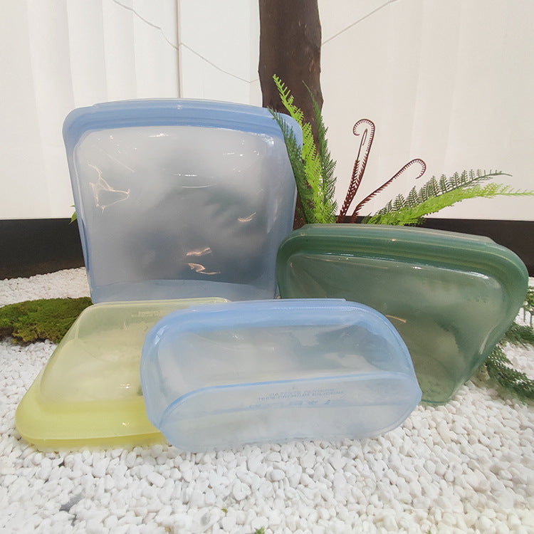Set of four silicone food storage containers with lids on a pebbled surface; Colorful food-safe silicone bags with airtight seal