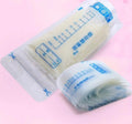 Roll of clear plastic bags with measurement markings on a pink background