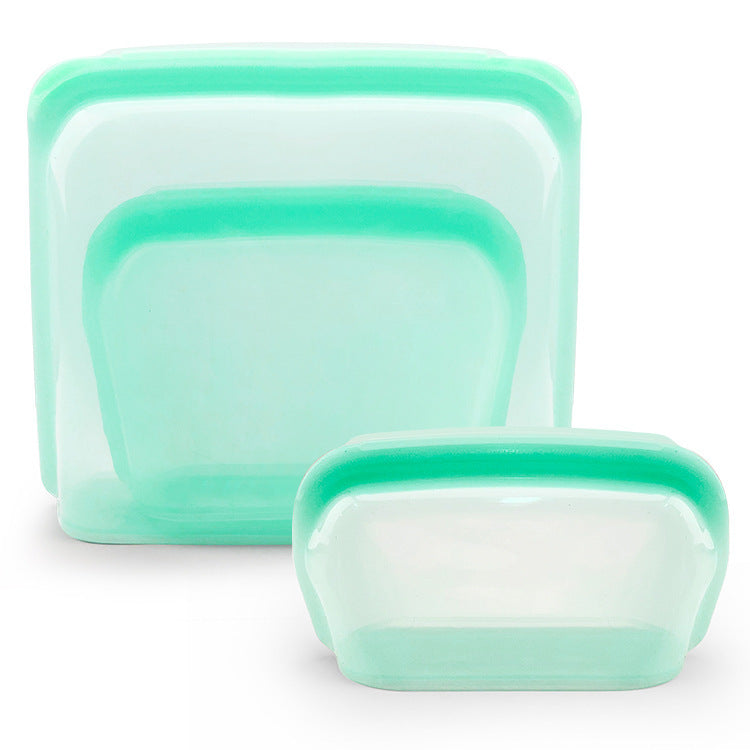 Set of three green silicone food storage containers on a white background