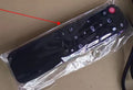 Remote control partially wrapped in clear plastic with a red arrow pointing to it.
