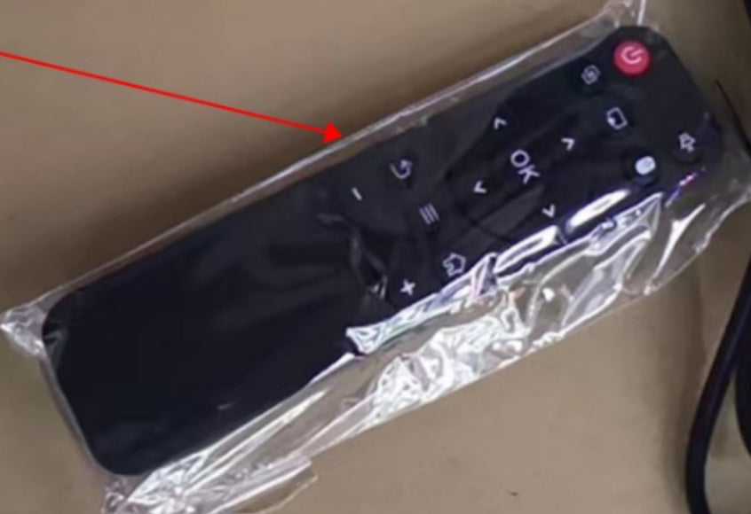 Remote control partially wrapped in clear plastic with a red arrow pointing to it.
