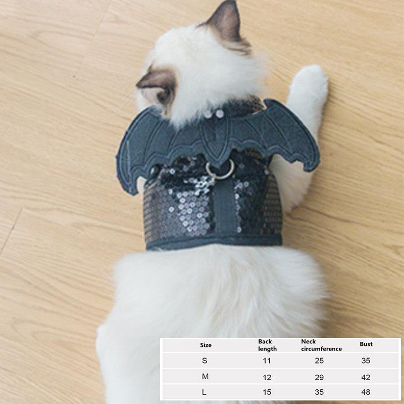 Cat wearing a sequined bat costume on a wooden floor with size chart overlay.