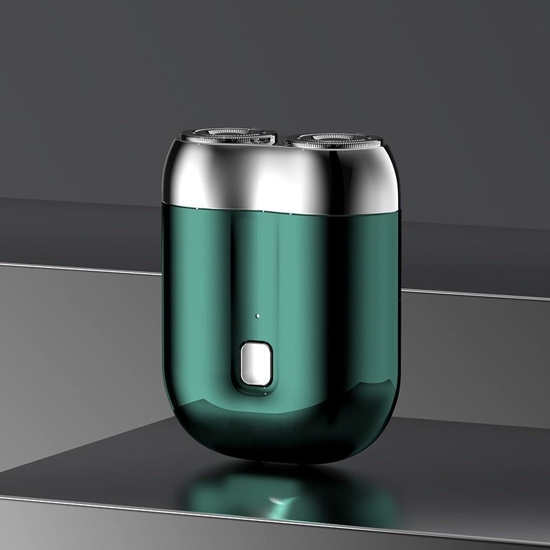 Green electric shaver with silver top on a reflective surface