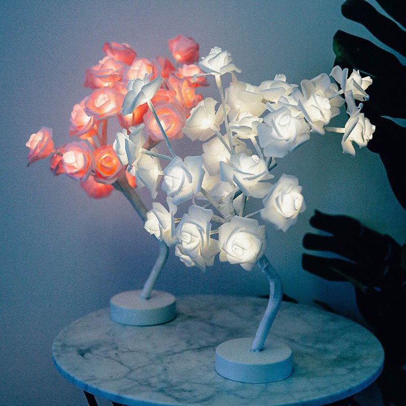 Two LED rose lamps, one red and one white, on a marble surface with a dark background.