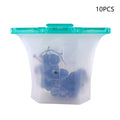 Silicone food storage bag with teal lid containing grapes on a white background