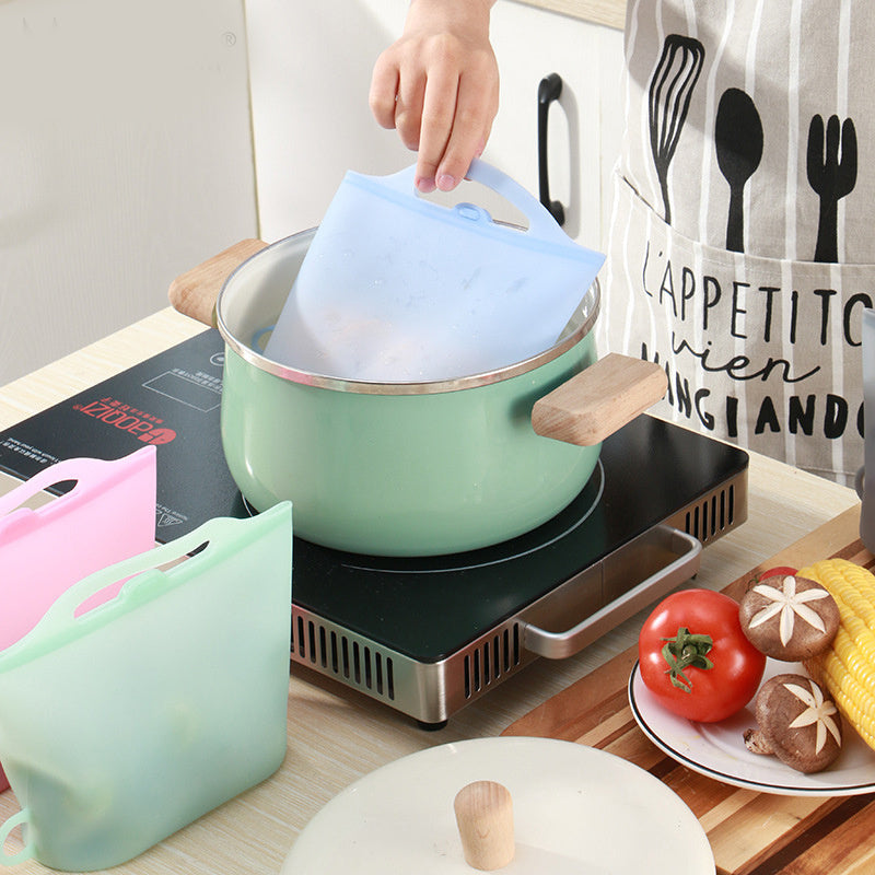 Person using a silicone lid on a pot with kitchen items and food in the background; Leakproof and BPA-free silicone storage bag for kitchen use