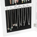 White jewelry cabinet with black interior displaying various necklaces.