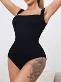 Person wearing a black romper jumpsuit or bodysuit against a white background