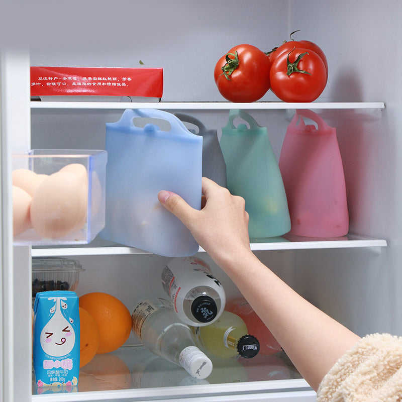 Person reaching into a refrigerator with colorful silicone bags; Square-shaped 1000ml silicone food storage bag in semi-transparent white