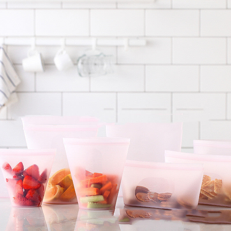 Clear plastic bags filled with various fruits and snacks on a white tiled wall background; Clear plastic bags filled with various fruits and snacks on a white tiled wall background