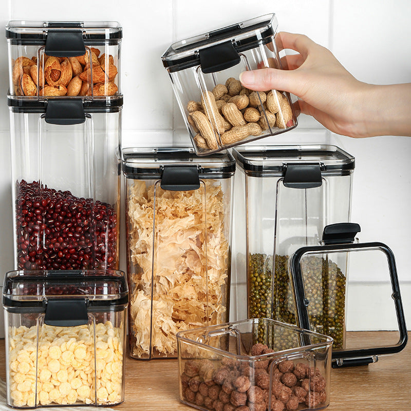 Set of clear food storage containers with black lids on a wooden surface