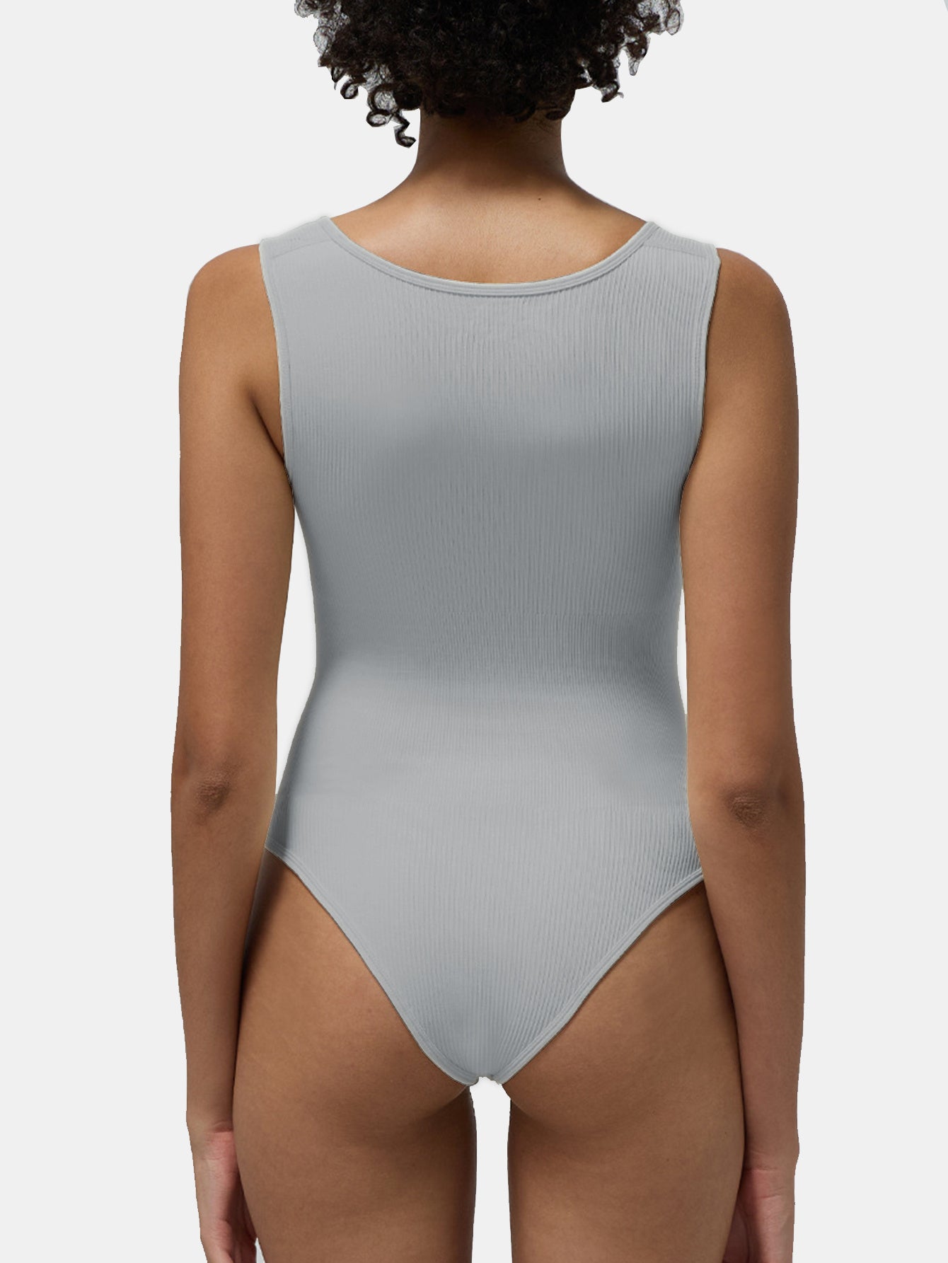 Person wearing a gray ribbed tank bodysuit on a white background