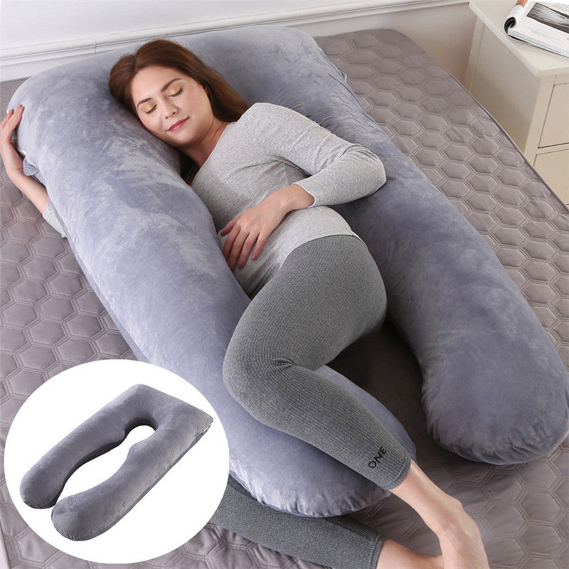 Woman lying on a large U-shaped gray body pillow on a bed