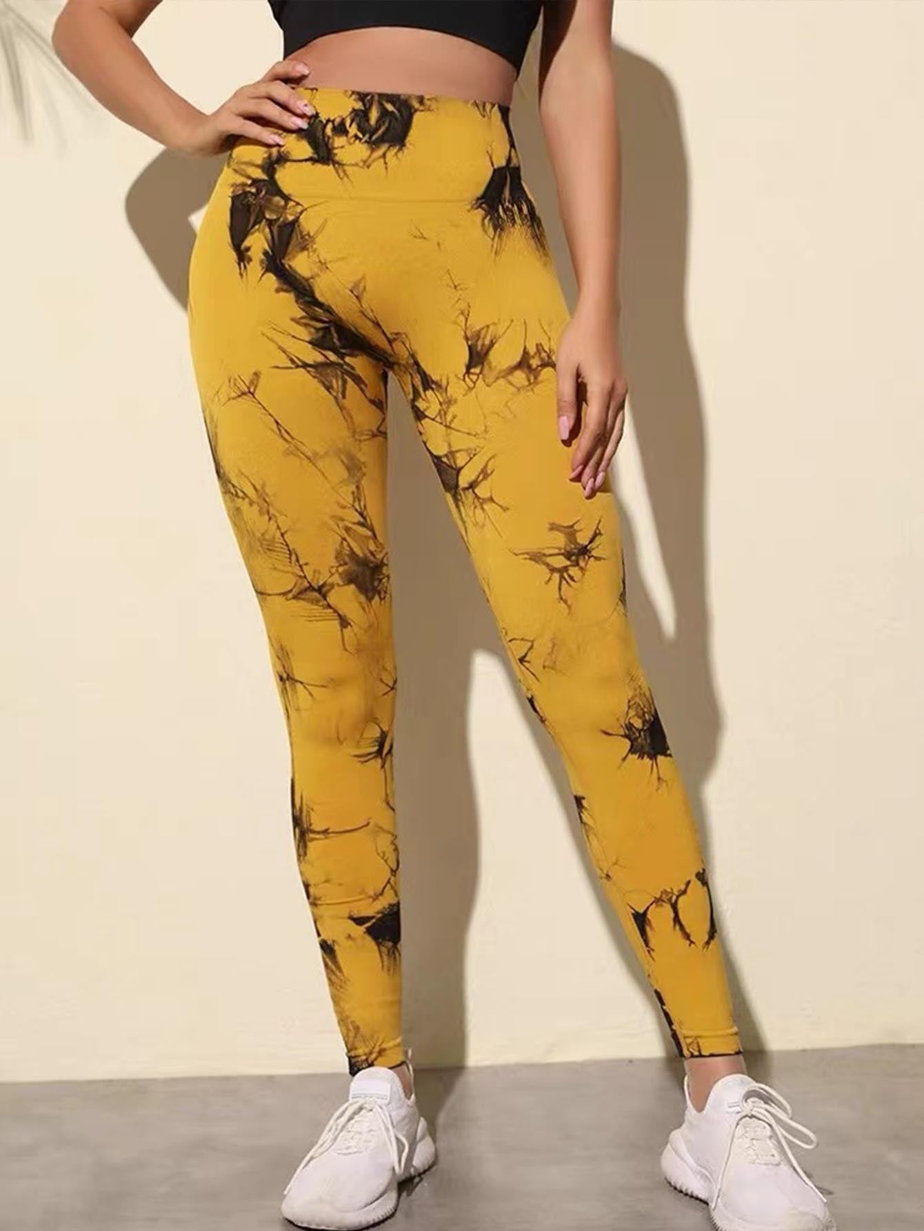 Yellow leggings with black floral pattern worn by a person on a plain background