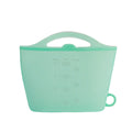 Mint green silicone measuring cup with handle on a white background; Eco-friendly food-grade silicone food pouch for lunch and snacks