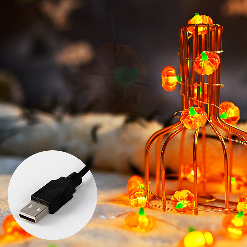 Halloween-themed string lights with pumpkins and a USB cable inset on a blurred background.