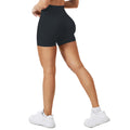 Person wearing black high-waisted shorts and white sneakers on a white background