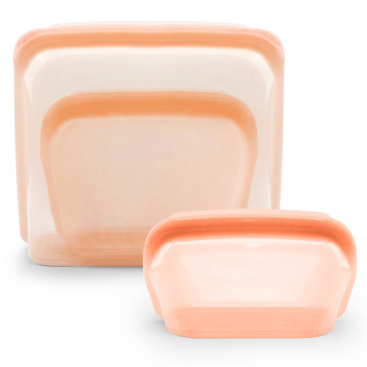 Set of silicone food storage containers with peach-colored lids on a white background