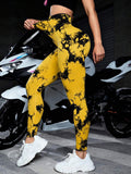 Person wearing yellow and black tie-dye leggings standing next to a motorcycle