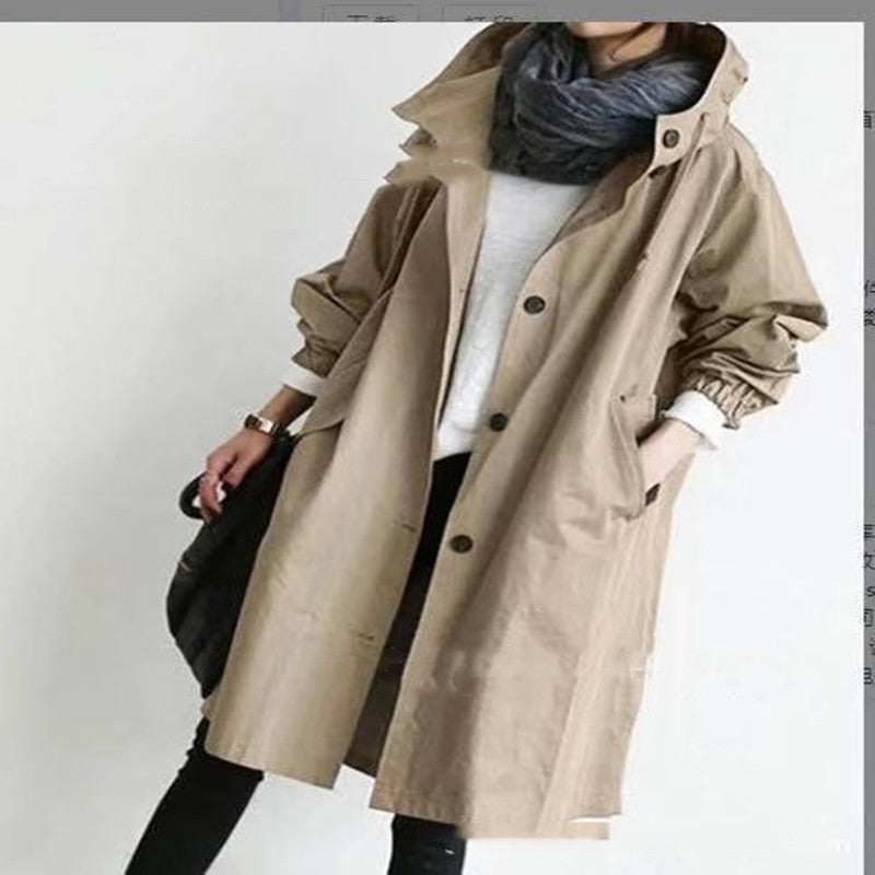 Person wearing a beige trench coat with a plain background