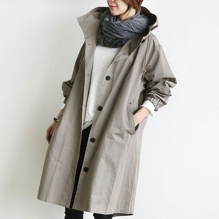 Person wearing a long gray hooded waterproof windbreaker on a plain background
